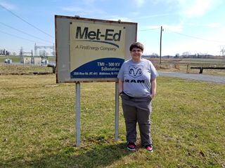 Elyse poses with an old Met-Ed sign near the Three Mile Island nuclear power plant.