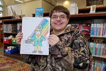 Elyse poses with the page that she colored at the McCormick Riverfront Library, showing a leprechaun with some magical beans.
