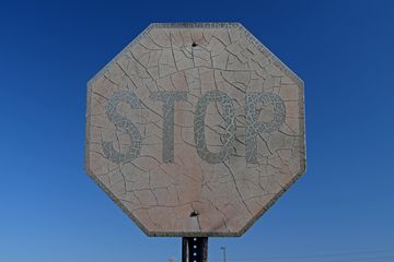 A very weathered stop sign outside of the JCPenney building.