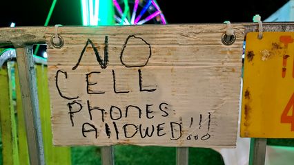 Handwritten sign disallowing cell phones on one of the rides.