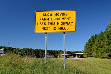 Sign warning that slow-moving farm equipment shares the highway with regular traffic on I-795, at the point where it merges with US 264 in Wilson.