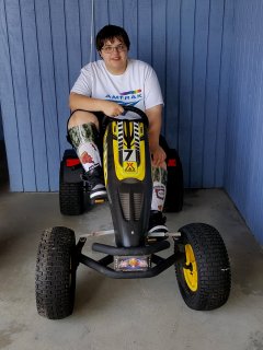 Elyse sits on some sort of all-terrain pedal vehicle at the KOA.