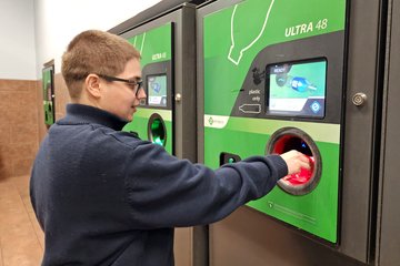 Elyse places a bottle inside the machine for recycling and gets a voucher for five cents.