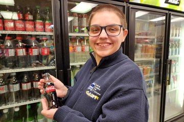 Elyse smiles for a photo with a tiny bottle of Coke Zero at JJ's Market.