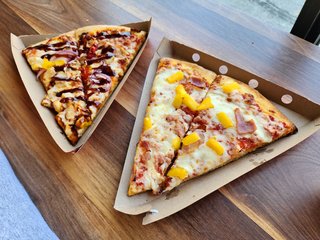 Elyse got two slices of pizza: one with chicken, onions, and barbecue sauce, and another with pineapple and back bacon.