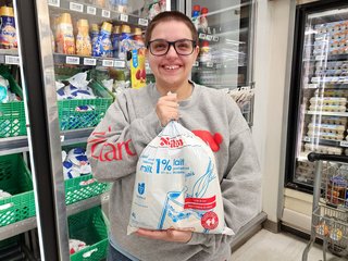 Elyse holds up a package of bagged milk.  This package contains two two-liter bags of 1% milk.
