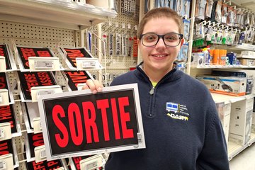 Elyse holds up a plastic "SORTIE" sign.  This came home with us, because while I couldn't justify a full-on commercial grade sign, this was much more reasonable.