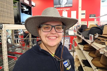 Elyse tries on a hat near the front of the store.