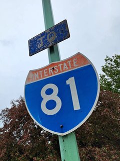 Interstate 81 sign with "TO" banner above it immediately after leaving the duty-free store's parking lot, and just before a second parking lot.
