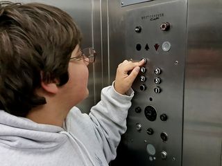 Elyse presses one of the floor buttons on the Allies garage elevator.