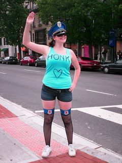 A woman wearing fishnet tights, short shorts, a tank top, and with badges saying "Hottie police", encourage motorists on Connecticut Avenue to honk their horns.