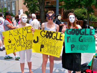 Three women hold three signs. "Ask me why I'm wearing a mask" is a common sign since Anonymous wears masks to their protests (since Scientology is known to retaliate against their critics), "Google Jeremy Perkins" refers to a person who ultimately flipped after his mother used Scientology treatments to help his mental illness, and "Google Fair Game Policy" refers to Scientology's practice of "Fair Game" as described above. Unlike many other protest groups I've demonstrated with, rather than simply displaying URLs, many Anon signs encourage people to do their own research, inviting them to use Google to search for the terms that get mentioned.