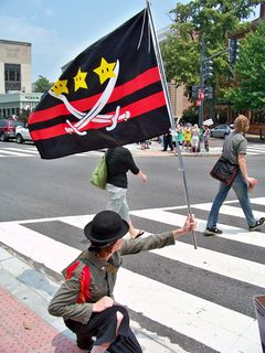 Wutman holds up a flag that Anonymous DC created specifically for this raid. It combines elements of the Sea Org emblem with elements of the flag of the District of Columbia.