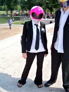 Now this was an interesting combination. This female Anon wore the black and white business suit of Anonymous, but then also wore a Pink Ranger helmet from Mighty Morphin Power Rangers. It was something of a mixed message, but it worked. The helmet is a life-size, detailed replica of the helmets that were used on Power Rangers and Zyuranger, though this one was made with the intention of using it for cosplay.