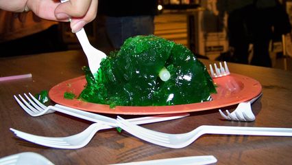 A person takes a piece of the gelatin mold shaped to look like a brain.