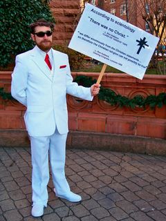 John McNonymous dressed in a white suit and held sign saying, "According to Scientology, 'There was no Christ,'" attributed to Scientology founder L. Ron Hubbard. The sign also quotes a 1958 lecture where Hubbard stated that, "we differ enormously from the Christian statements ... so therefore the Christian religion cannot possibly be true."