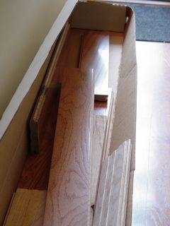 In the hallway, a peek in a box reveals the hardwood flooring, waiting to be installed.