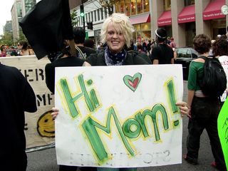 In what I would consider the lighter side of protests, this woman carries a message of "Hi, Mom!" on the back of her sign.