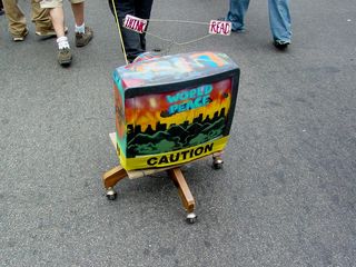 Meanwhile, a person drags a television on wheels, creatively painted up and wrapped in caution tape.