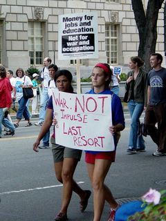 Another woman carries a sign stating that war should not be an impulse, but rather a last resort.