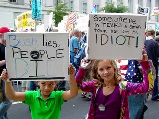 Here, two young participants display their signs disapproving of George W. Bush for the camera.