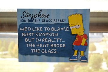 Sign in the Sunsphere about a shattered glass panel on the exterior, referencing the moment on The Simpsons when Nelson threw a rock at the Sunsphere, causing it to fall over.