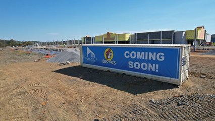 A large banner hung from a shipping container announcing that a new Buc-ee's was coming soon, visible from the highway.