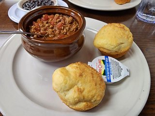 Lunch, consisting of a bowl of chili and two pieces of cornbread.