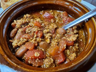 Lunch, consisting of a bowl of chili and two pieces of cornbread.