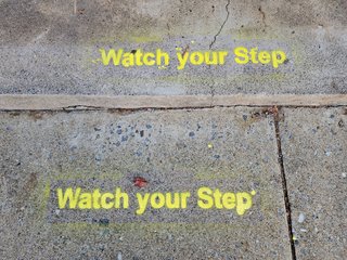 "Watch your step", spotted a tad too late.  A sign higher up, on the door or the window, would be far more helpful.  Even more helpful would be to eliminate that step altogether and make it slope up to the entrance instead of that tiny step.