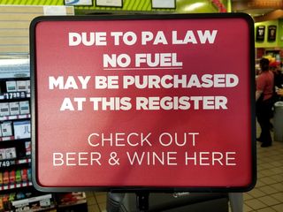 Signs advising patrons of a requirement that fuel and alcoholic beverages must be purchased at separate registers.