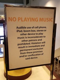 Behavioral signs in the mall.  One sign bans the wearing of pants lower than the waist (i.e. no "droopy drawers"), and the other bans the playing of audible music.