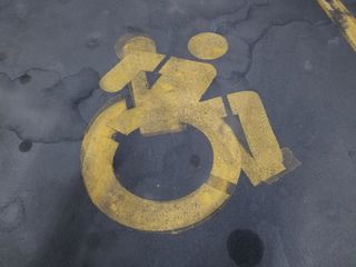 I spotted this in the garage where we parked the car.  Someone painted the new wheelchair symbol over the old wheelchair symbol.