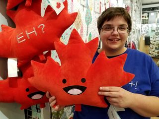 A maple leaf pillow with "Eh?" embroidered on the back at Quilts Etc. elsewhere in the mall.