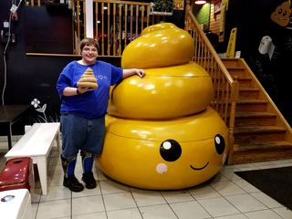 Elyse poses with a giant poop located near the entrance, and holds a stuffed poop alongside it.