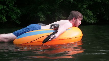 Adam uses a pair of flip flops as paddles to propel himself through the water.