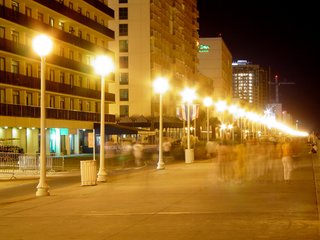 On the boardwalk, the lights shine brightly, and ghostly images of people walking by can be seen, a byproduct of long-exposure photography.
