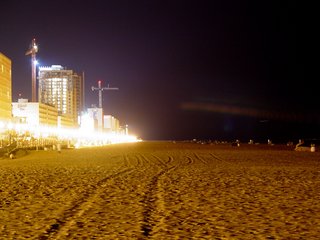 The beach itself, meanwhile, is lit by the lights of the boardwalk, while showing the marks of a day of people walking across it, judging by all the footprints.