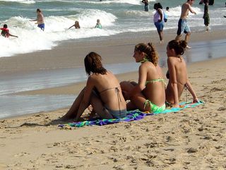 South of the fishing pier, a group sits on towels and watches the surf.