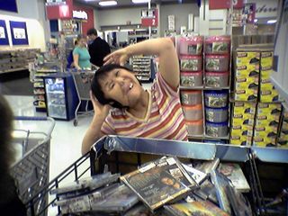 Becky is making funny faces in front of the big DVD bin...