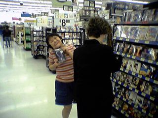 Peeking out from behind Rebecca, Becky holds up some kind of movie (can't tell what it is).