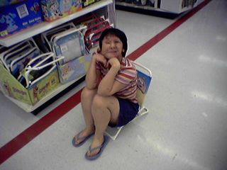 Becky takes a break during our shopping trip, alighting on this fold-up chair.  I think the chair's just a wee bit too short, but otherwise, pretty good.