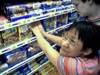 Becky tries unsuccessfully to get a package of cookie dough back on the shelf.  Turns out there was a barrier on there that she was missing.