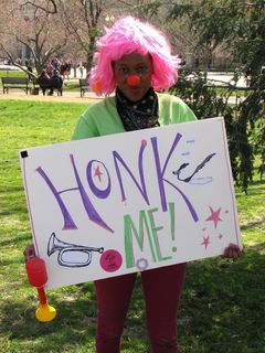 One of the members of the clown troupe holds a "HONK ME!" sign inviting passers-by to honk the attached horn. This was the "hook" to get people to participate further.