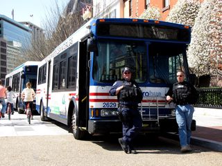 Police officers stand next to a Metrobus, waiting to pick up any arrestees for the civil disobedience action planned for later.