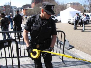 A SWAT officer cordons off an area of Pennsylvania Avenue with police tape.