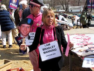 Medea Benjamin holds up Bradley Manning masks and "I AM BRADLEY MANNING" signs.