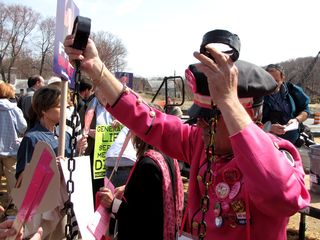 Another Code Pink volunteer hands out prison-striped costumes, and chains to go with the costume.