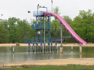 The tower at Shenandoah Acres in Stuarts Draft, in its final incarnation as home of the Pink Zipper slide, seen here on May 3. The end of the slide normally would be closer to the water, but the lake's water level was lower than where it would normally be when the facility was still in operation (Shenandoah Acres closed in 2004). This tower previously held a cable ride, where guests would hold onto handlebars and slide down a long cable from the uppermost level. This is likely one of the last pictures of the tower ever taken, because the tower was demolished later that year.