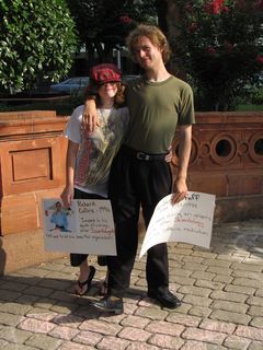 Hunter poses with his girlfriend, both holding signs remembering victims of Scientology.